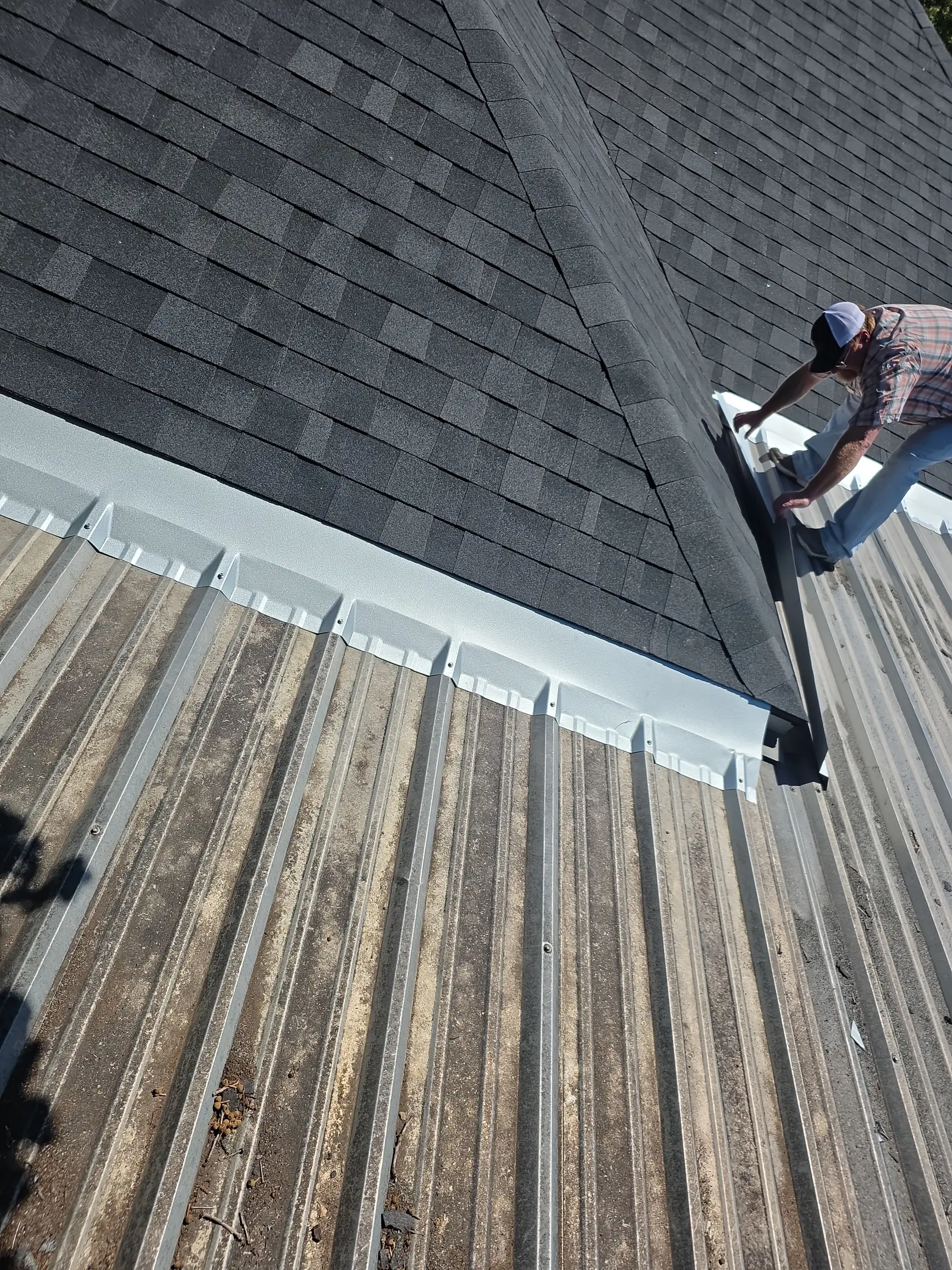 Technician working on a shingle-to-metal roof transition